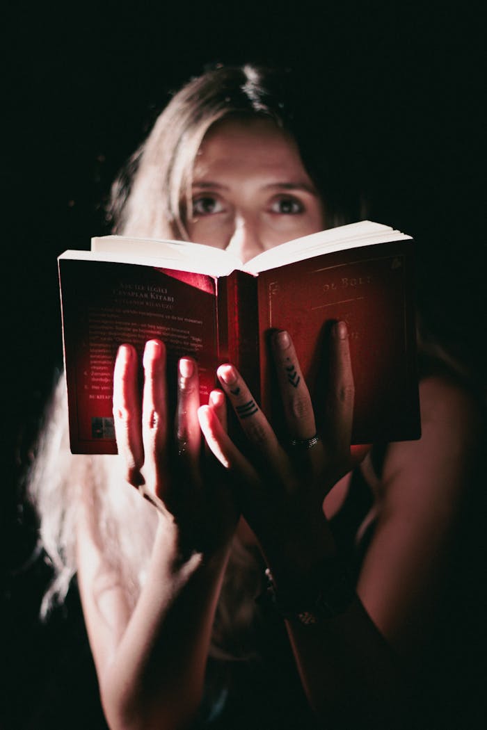 A woman reading a book in a dimly lit setting, emphasizing mystery.