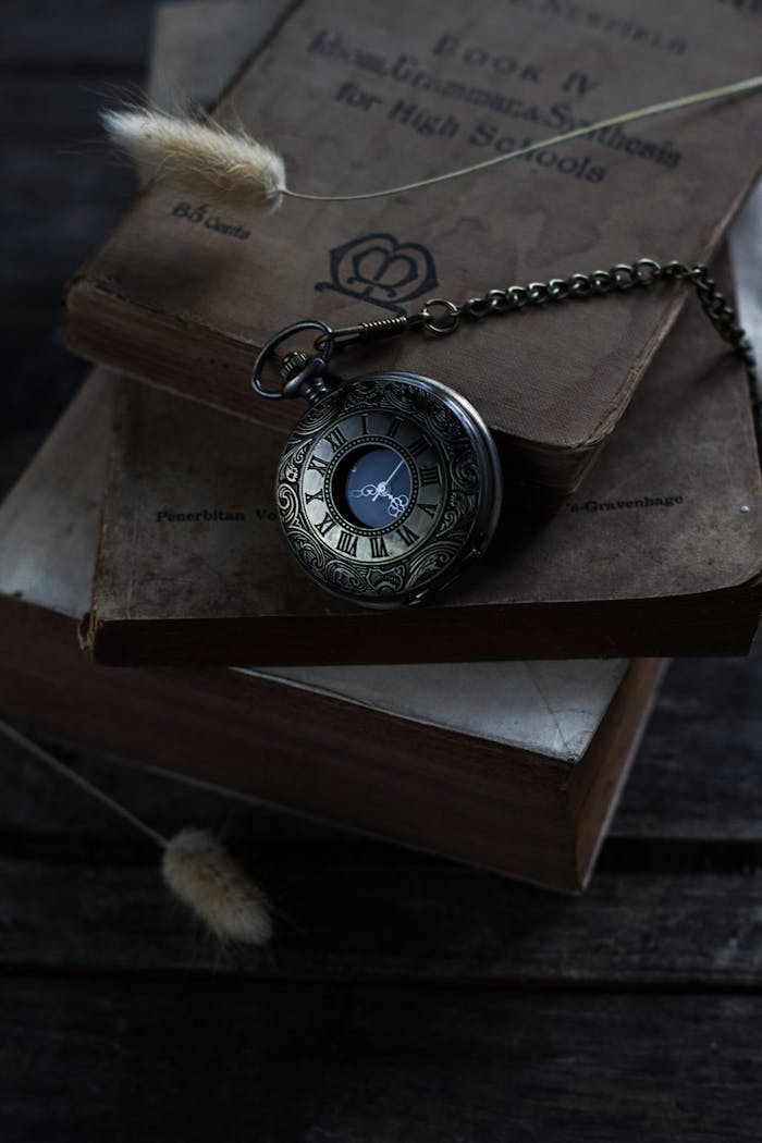 Elegant vintage pocket watch resting on stacked old books, perfect for timeless themes.