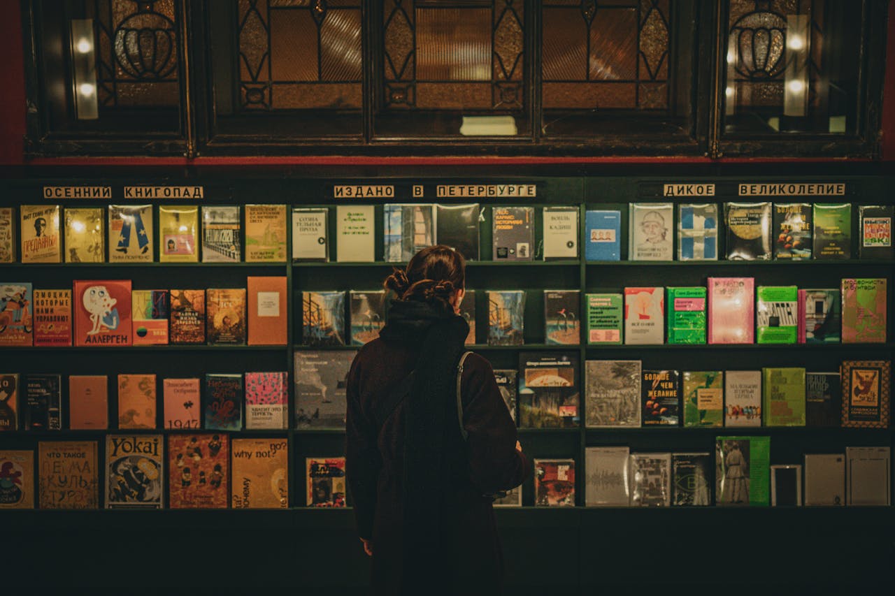A woman selecting books from a well-lit shelf in a Saint Petersburg library.